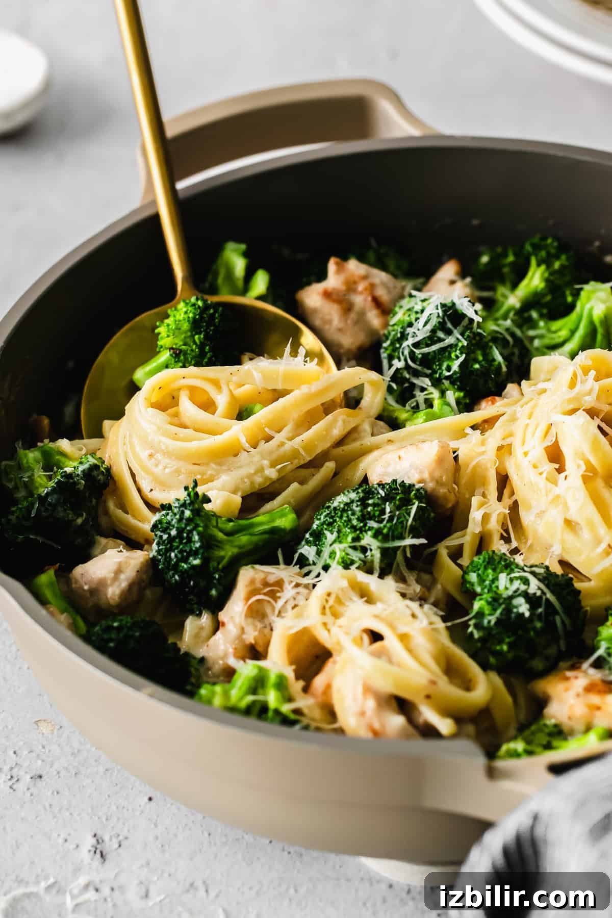 A spoon full of fettuccini noodles and broccoli. 