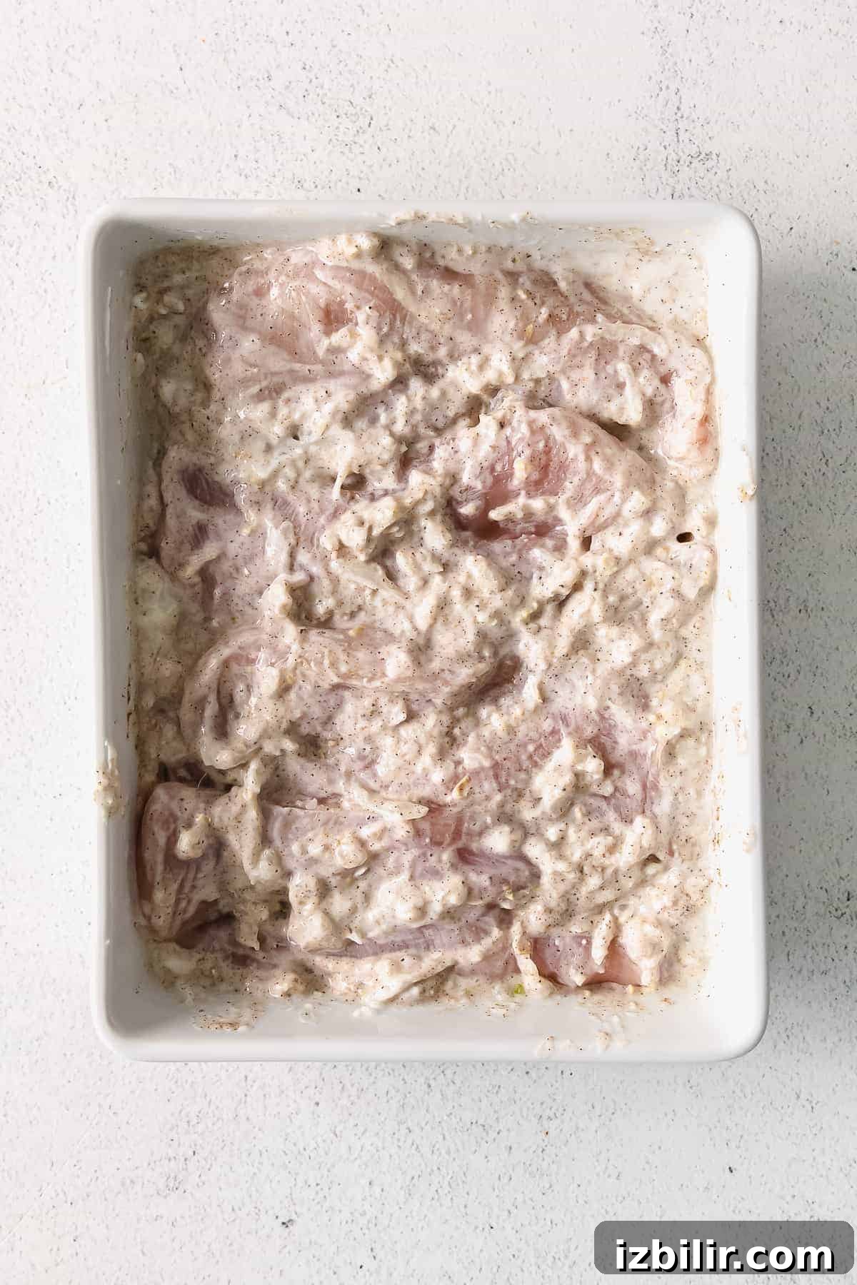 Chicken thighs marinating in Greek yogurt.