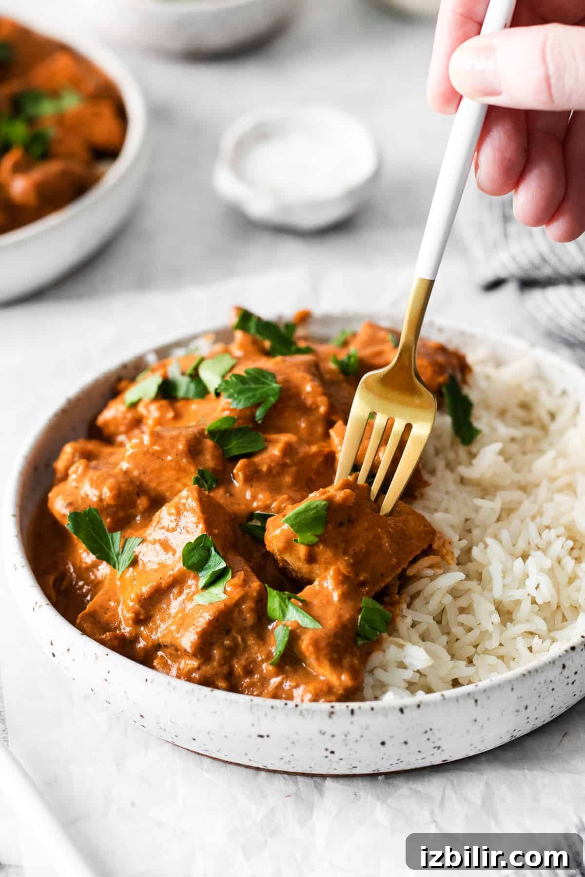 A fork digging into butter chicken.