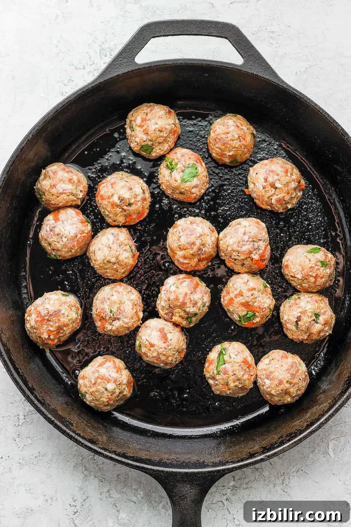 Browning meatballs in a cast iron skillet.
