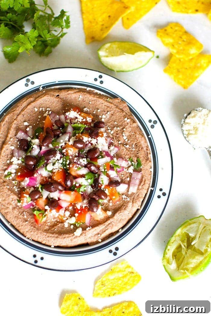 mexican black bean hummus in a bowl topped with cotija cheese and diced tomatoes