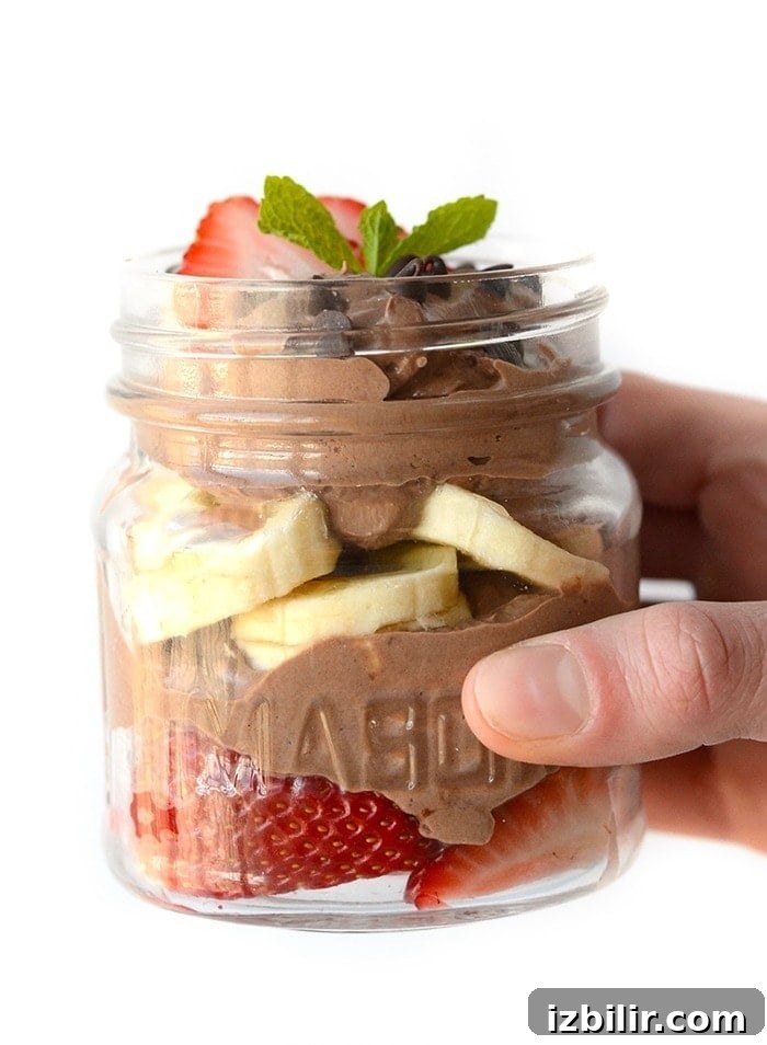 healthy chocolate peanut butter mousse as a parfait with sliced strawberries and sliced bananas