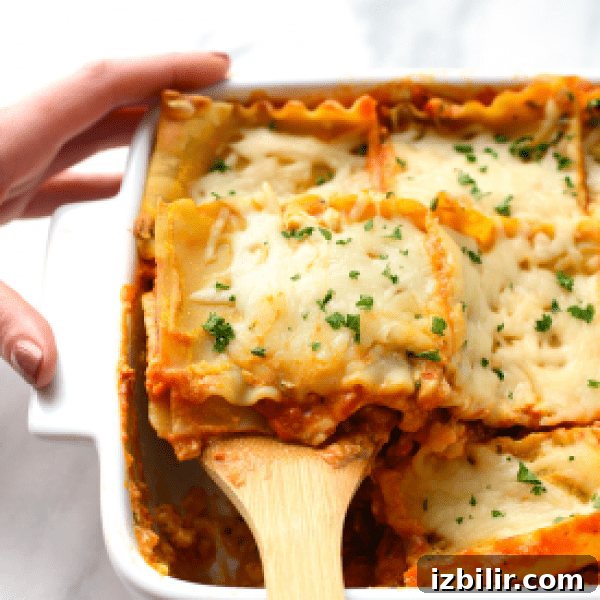 Vegetarian Sweet Potato Lasagna Recipe 2 Lasagna in a white dish with a wooden spoon.