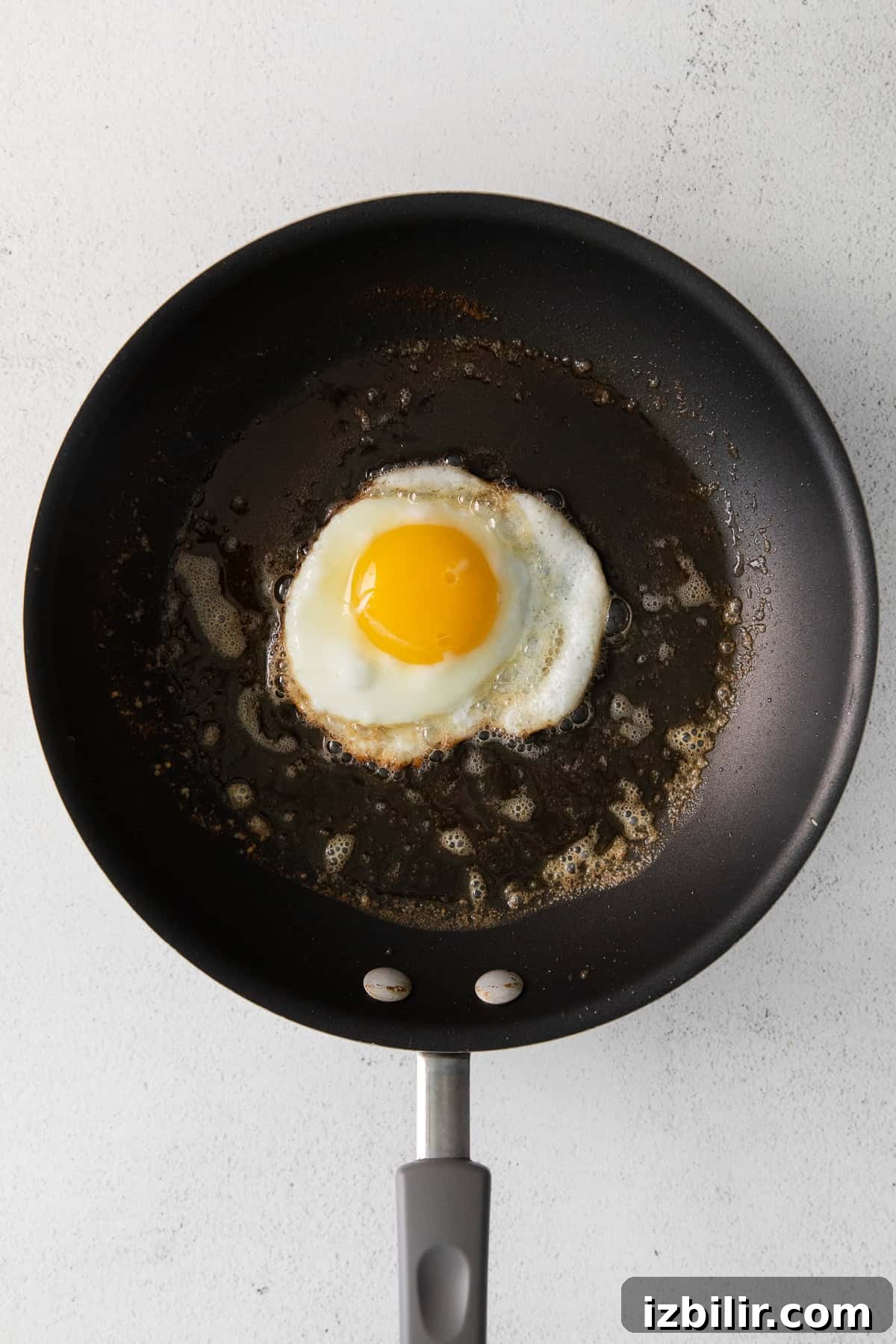 How to Fry an Egg for a Runny Yolk and Crispy Edges 5 Frying an egg in butter in a nonstick pan.