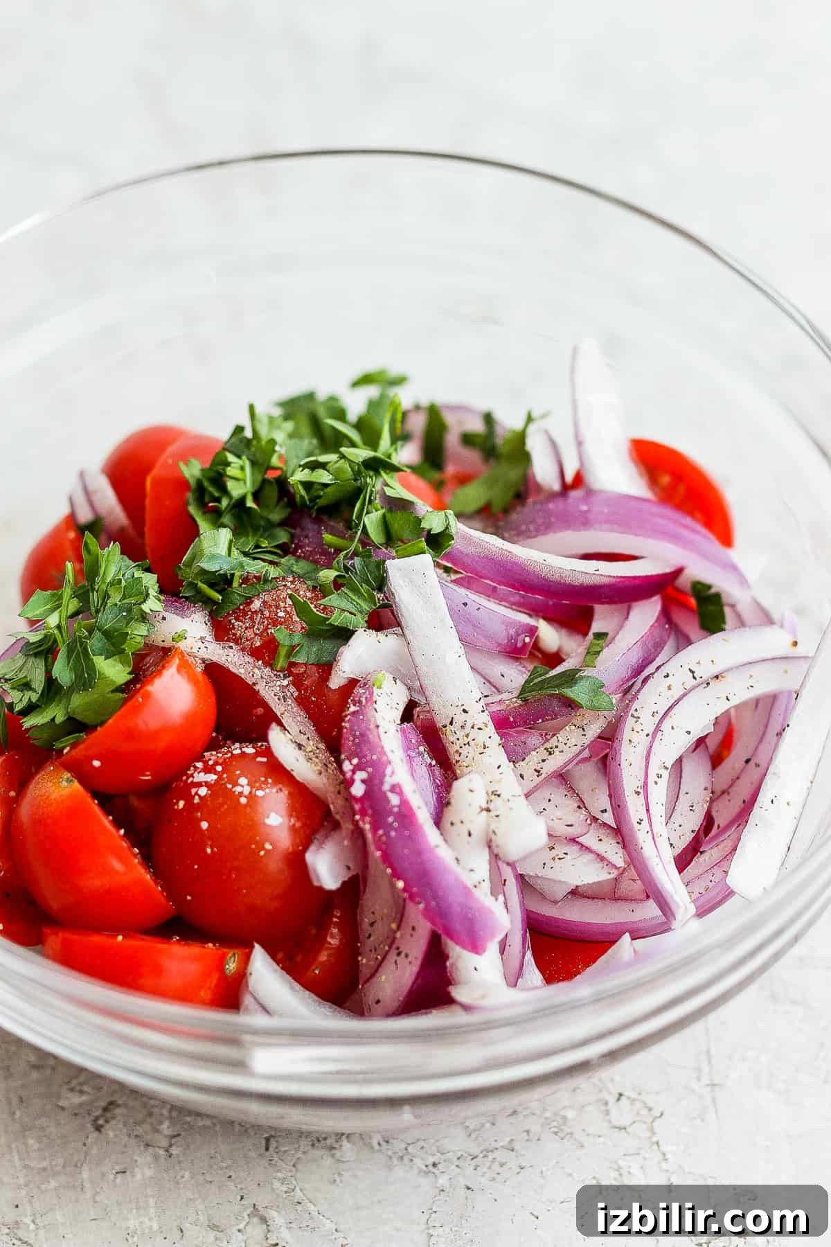 Classic Nicoise Salad Recipe 6 tomatoes, onion, and parsley in a bowl.