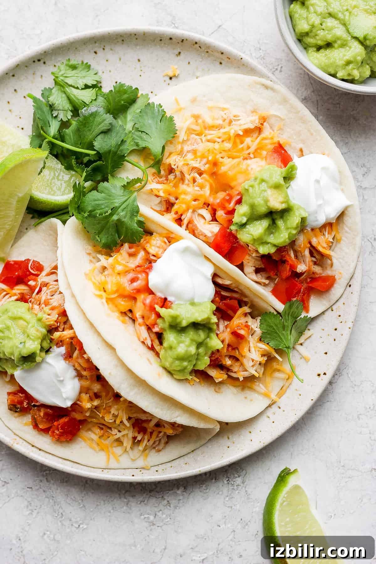 The most tender, flavorful Crockpot Chicken Tacos made with just 4-ingredients! chicken tacos on plate.