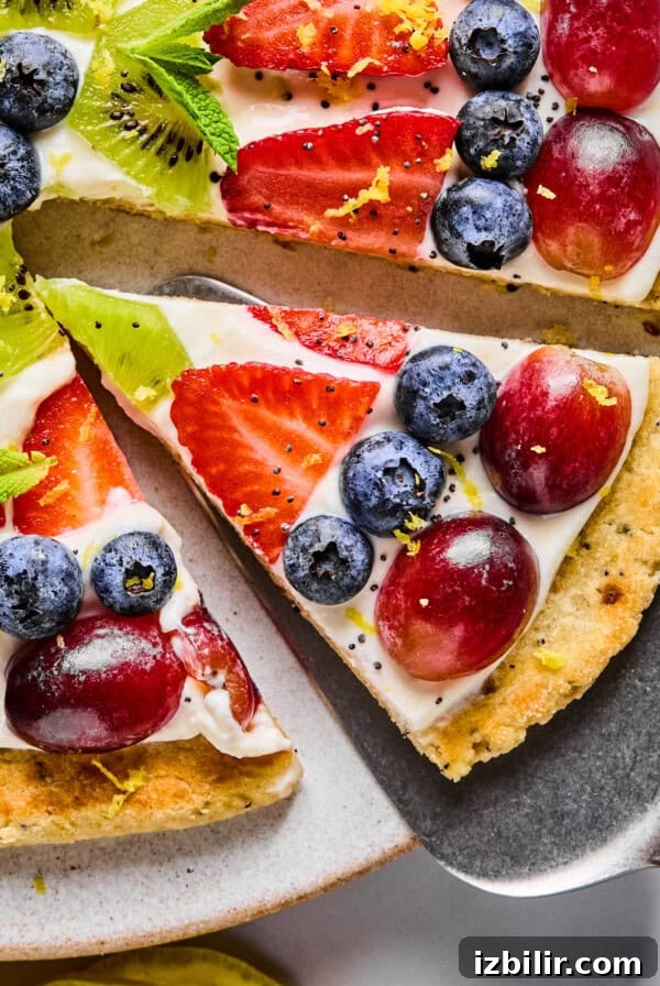 A slice of fruit pizza topped with blueberries and strawberries.
