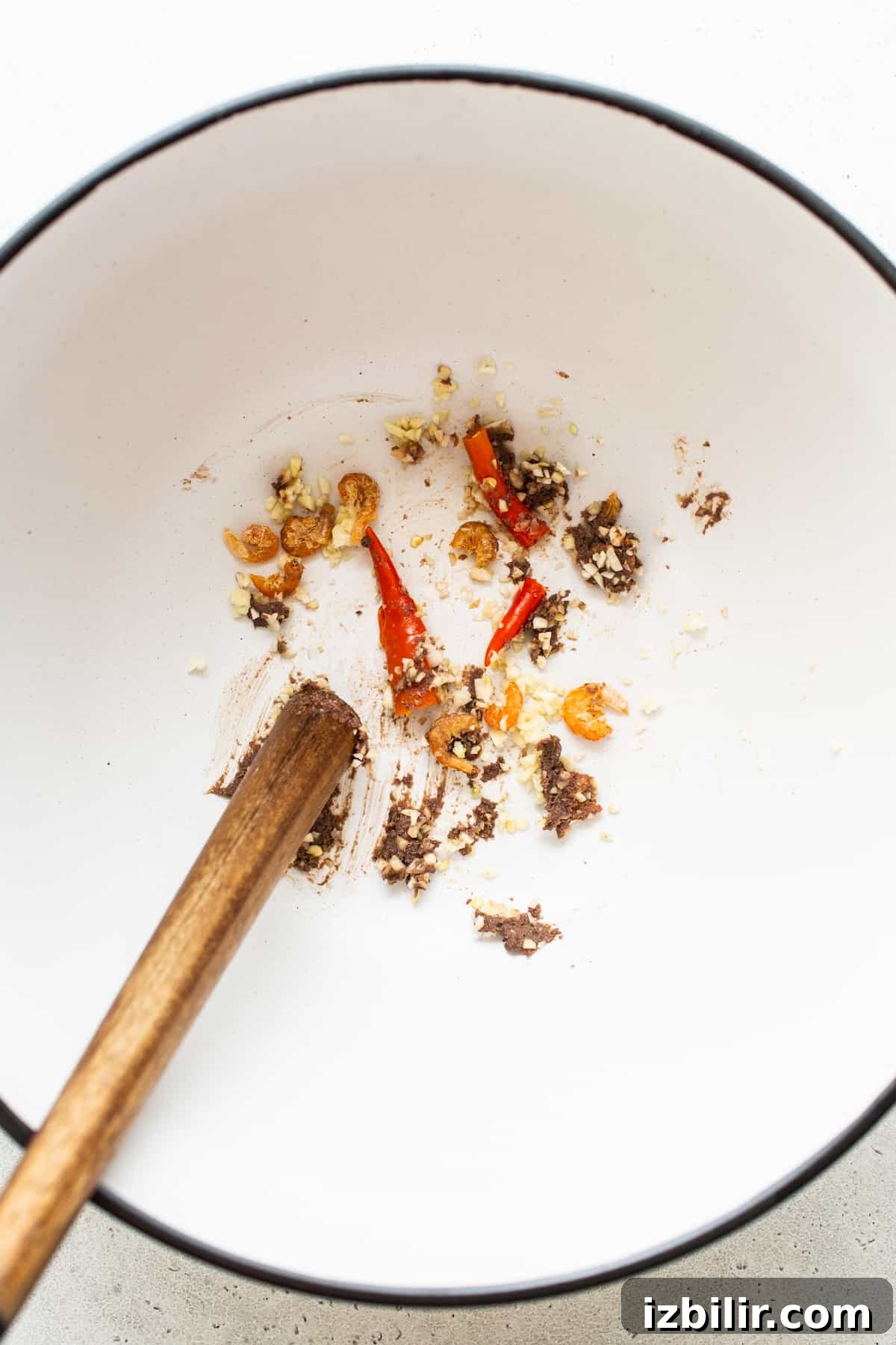 Crushing chili peppers and dried shrimp for papaya salad. Thai chili peppers and dried shrimp being smashed.