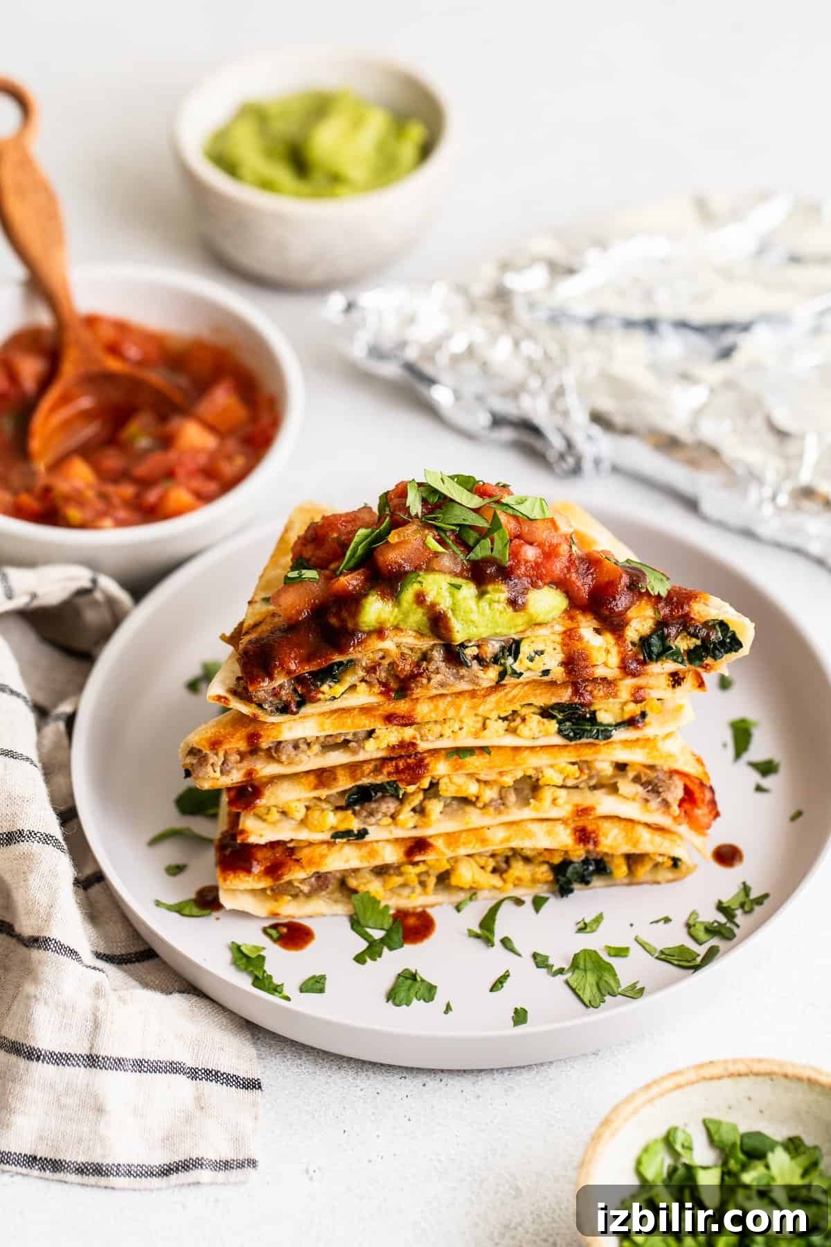 Slices of breakfast quesadillas on a plate topped with salsa and guacamole.