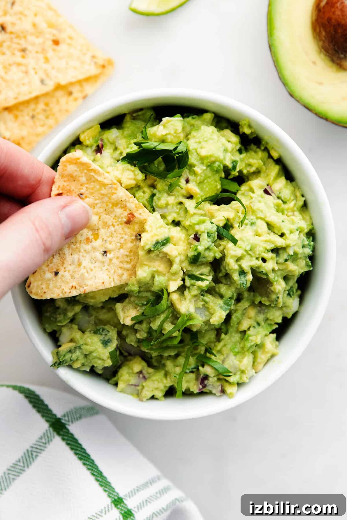guacamole in bowl with hand dipping