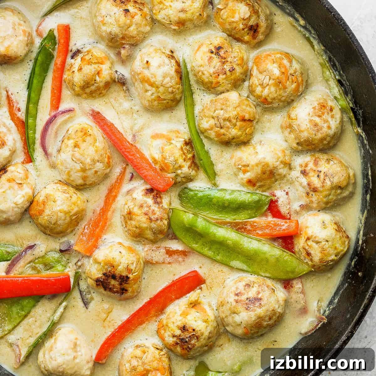 Thai Green Curry Chicken Meatballs 2 Chicken meatballs and vegetables simmering in a cast iron pan.