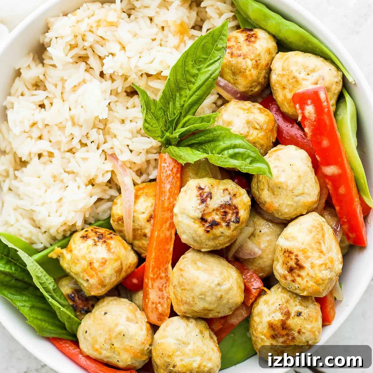 Thai Green Curry Chicken Meatballs 13 Chicken meatballs, vegetables, and rice in a bowl.