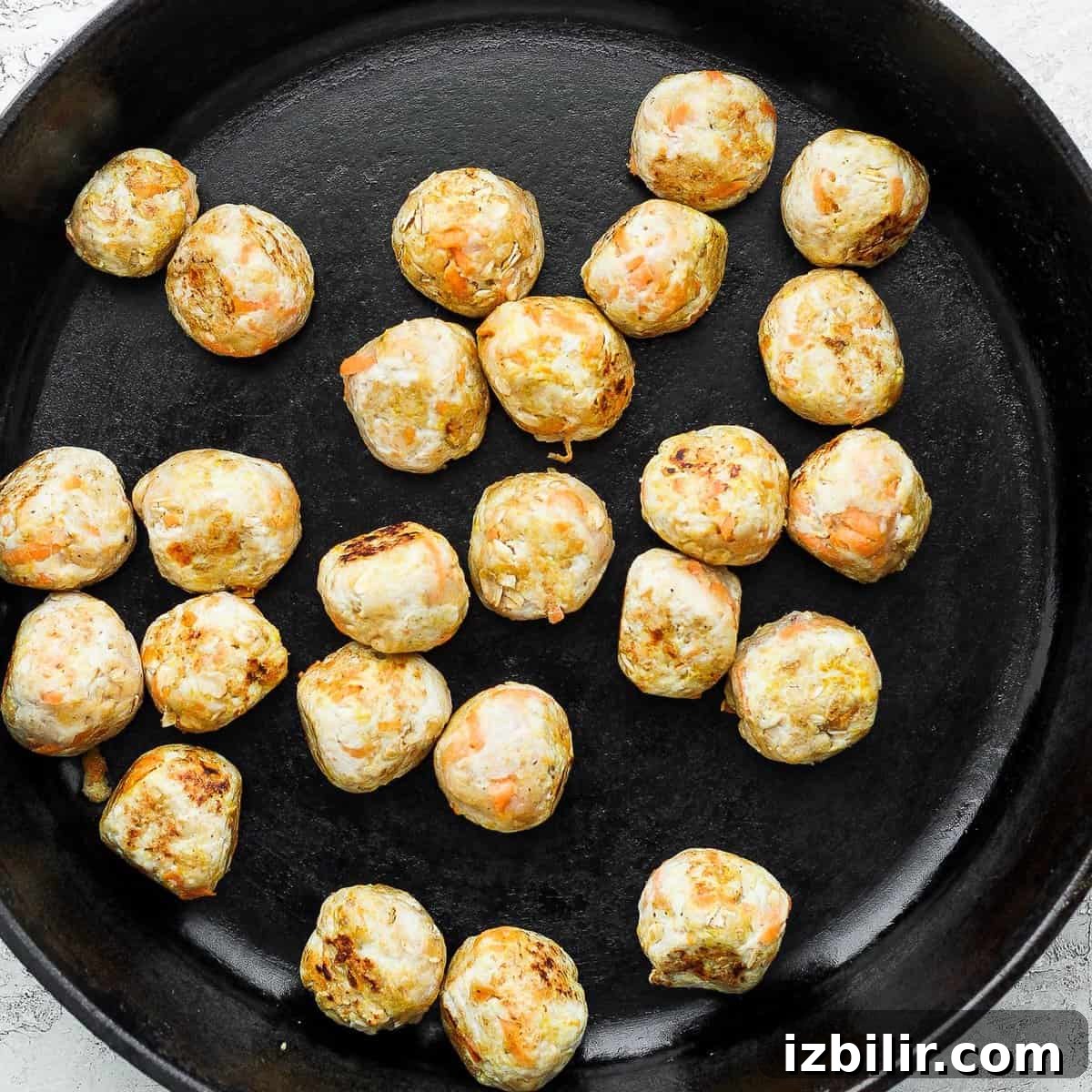 Thai Green Curry Chicken Meatballs 4 Chicken meatballs browning in a cast iron pan.