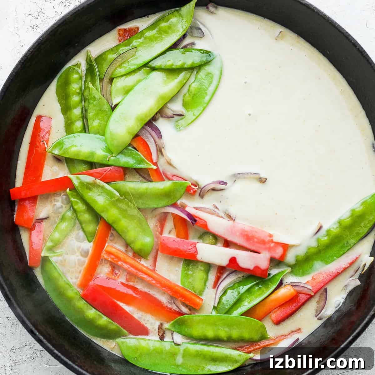 Thai Green Curry Chicken Meatballs 10 Green curry and vegetables in a cast iron pan.