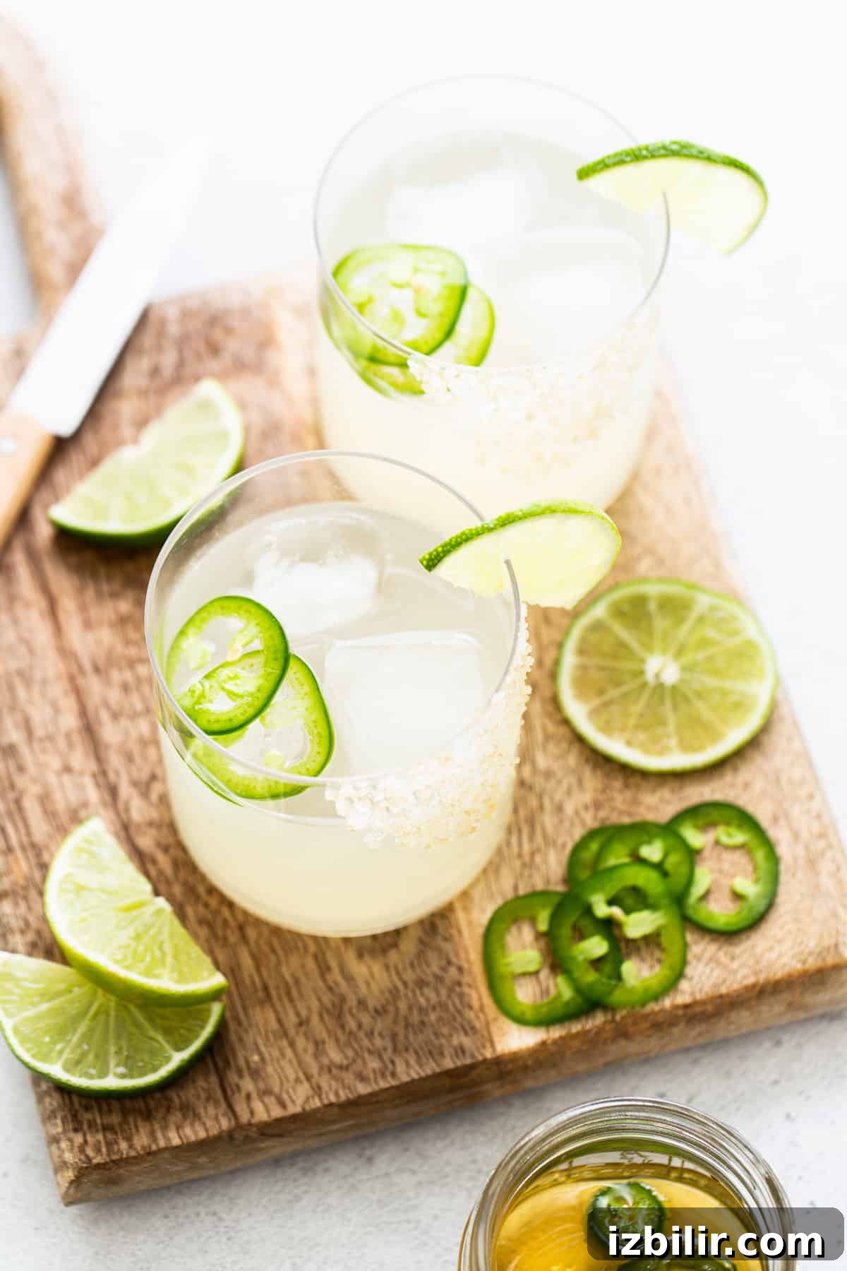 Two spicy mezcal margaritas on a cutting board.
