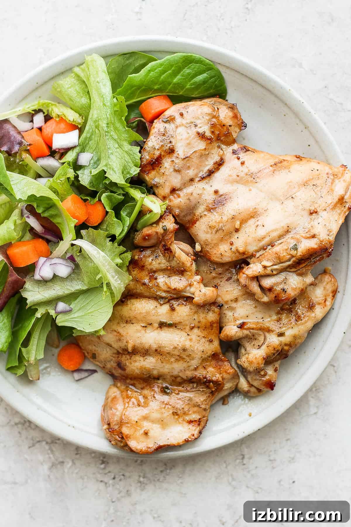 Served grilled honey mustard chicken thighs. Grilled chicken thighs on plate with greens.
