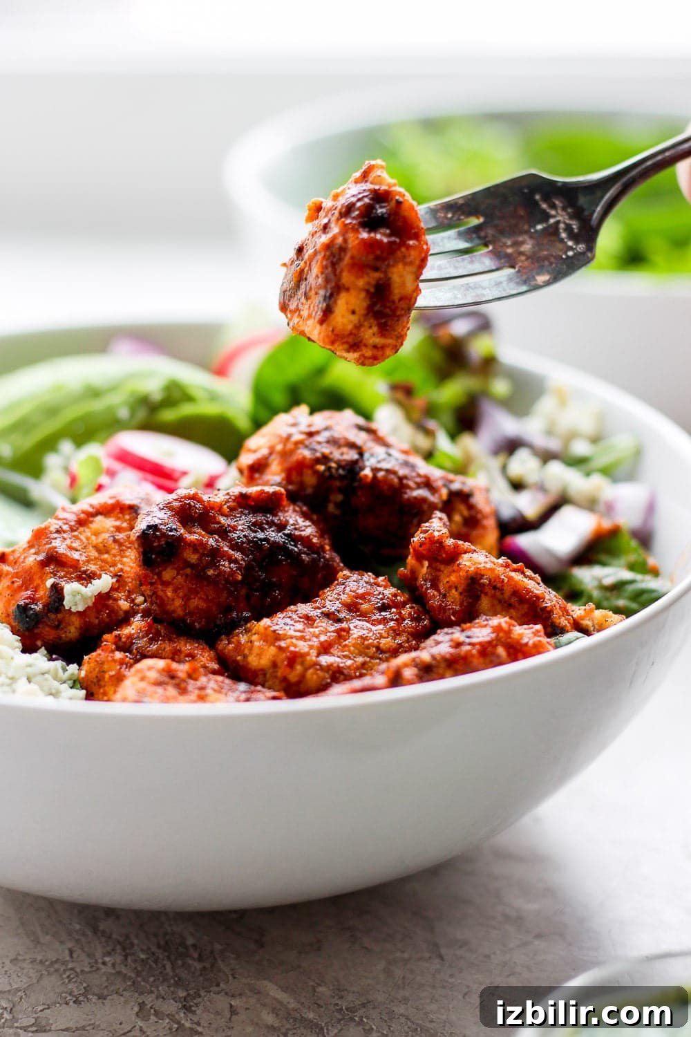 Fit Foodie Cooking Club May 2022 Recipes and Meal Plans 4 A piece of sriracha chicken on a fork