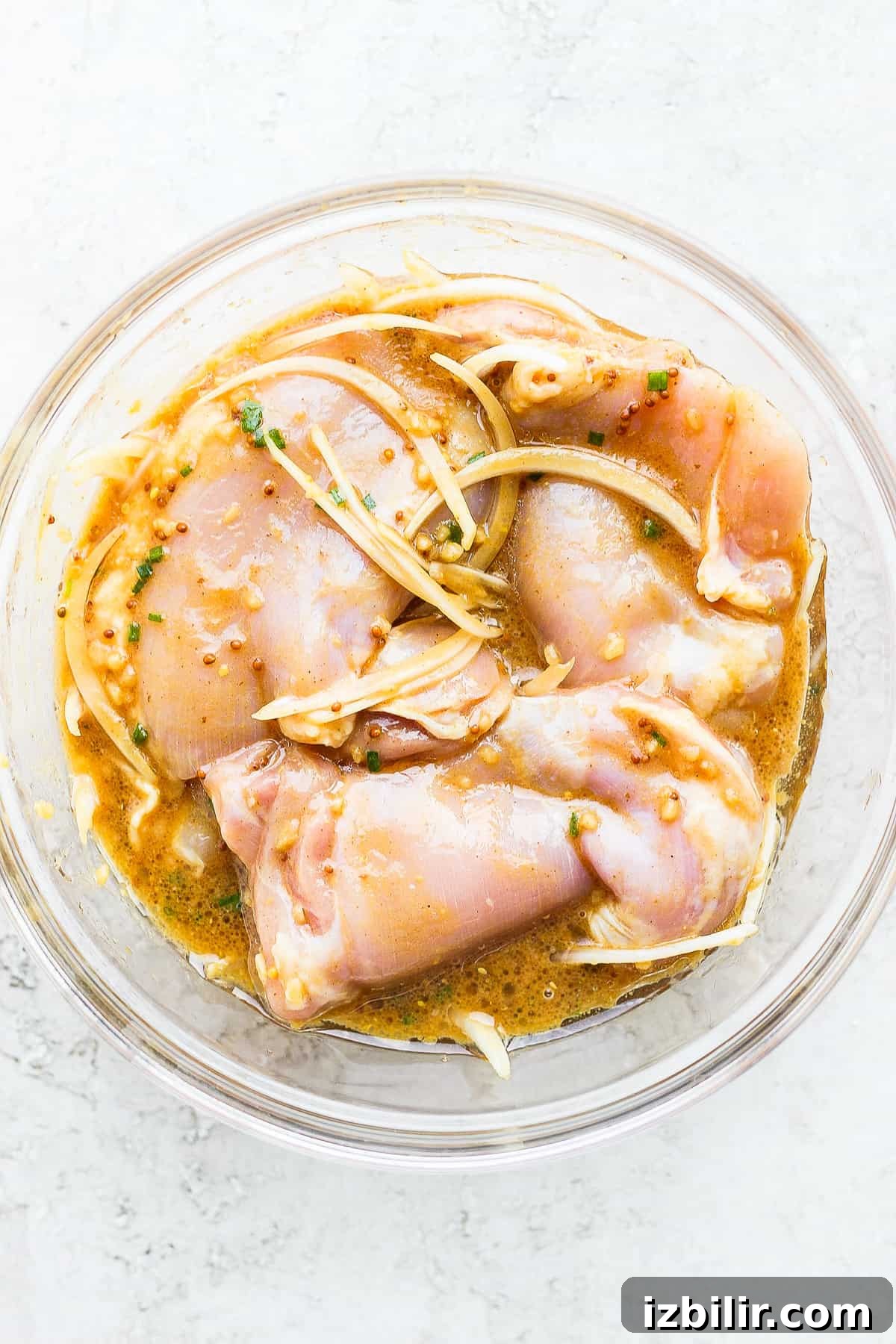 Savory Marinade for Juicy Chicken Thighs 2 Chicken thighs marinating in a bowl.