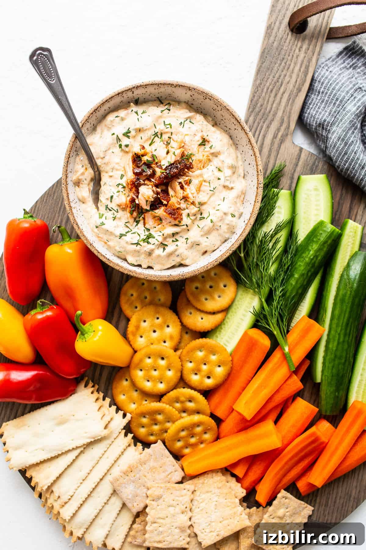 Smoked salmon dip in a bowl with crackers and veggies.