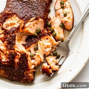 A piece of salmon on a plate with a fork.