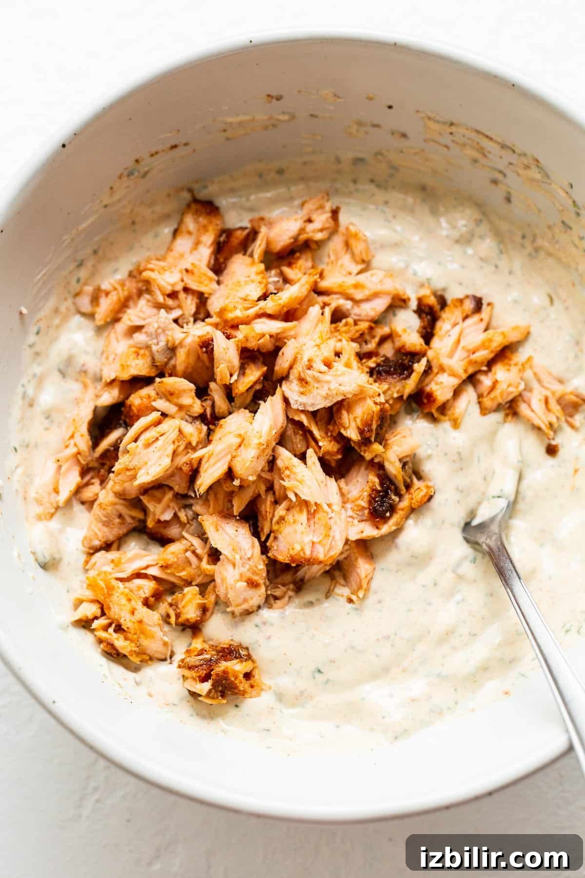 Flaked smoked salmon in a bowl with cream cheese mixture.