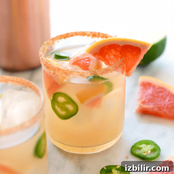 Two glasses of grapefruit margarita with jalapeos and limes.