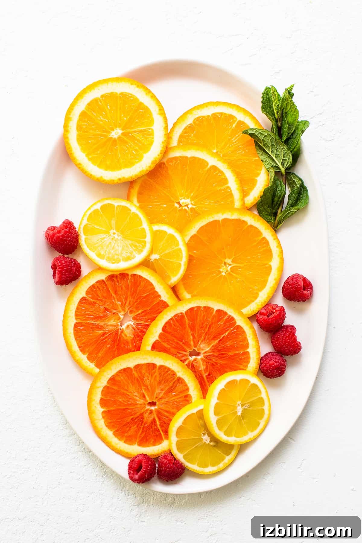 How to Make a Classic White Wine Spritzer 3 Fruit and fresh herbs on a white plate.