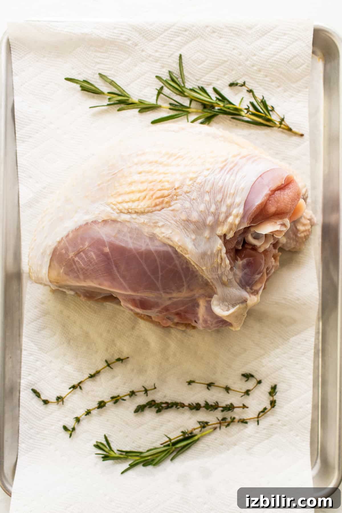 Smoked Turkey Breast Recipe for Juicy, Flavorful Meat 3 A turkey breast on a paper towel and fresh herbs.