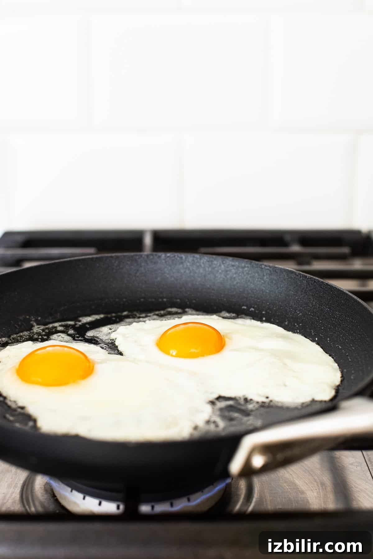 Eggs frying in a skillet to over medium.