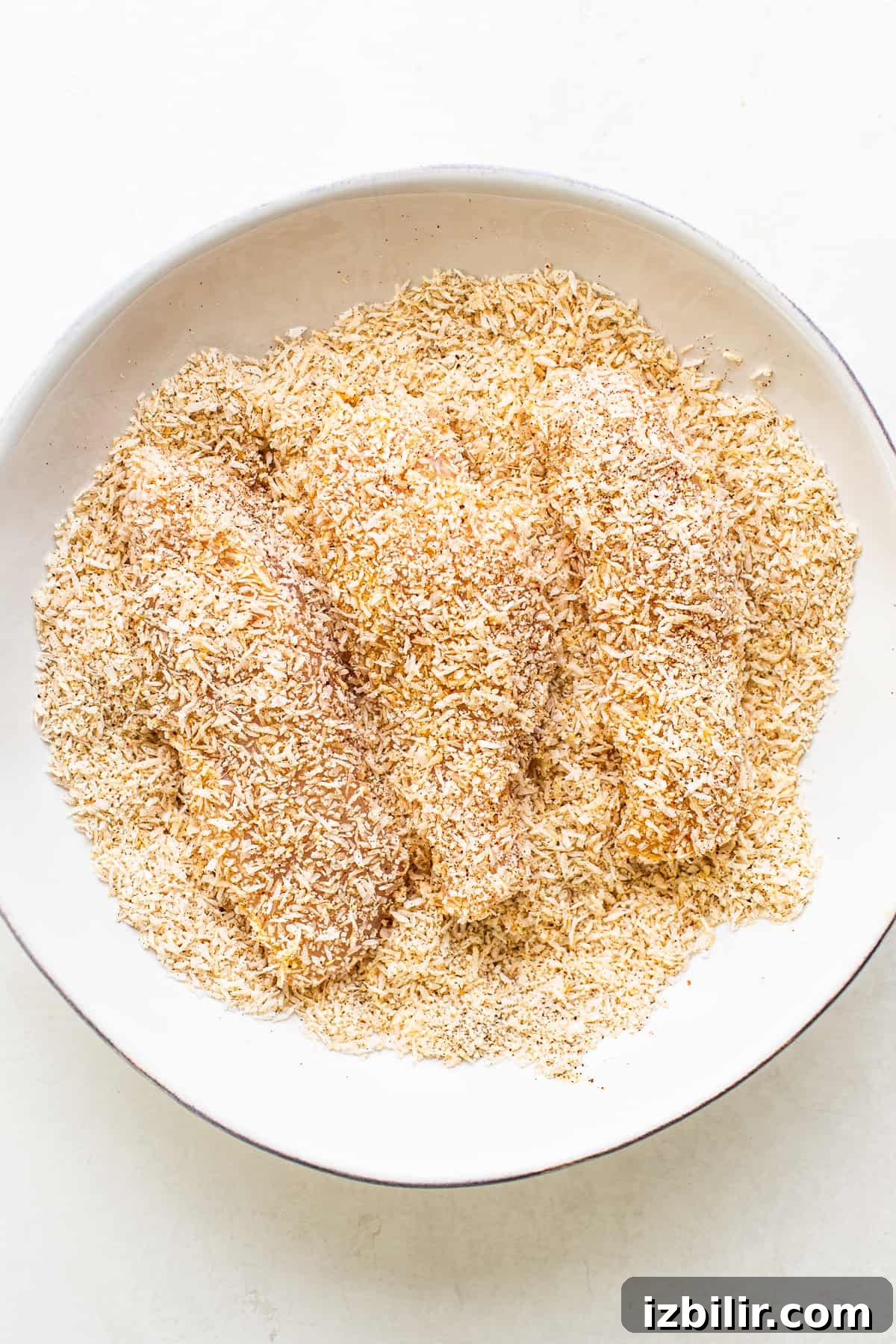 Raw chicken tenders breaded in a bowl.