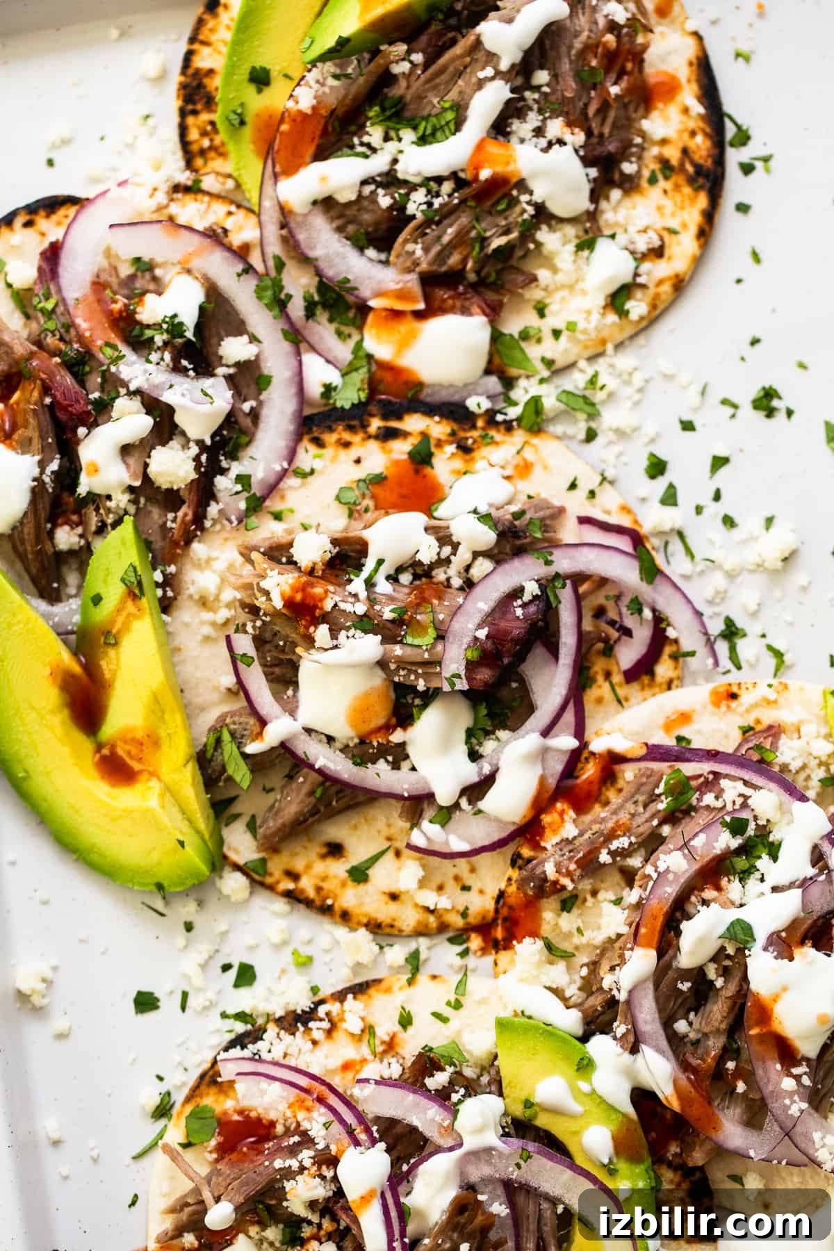 These smoked pulled pork tacos are made with our incredible, fall-off-the-bone smoked pork shoulder and all the best toppings. shredded pork tacos with toppings.