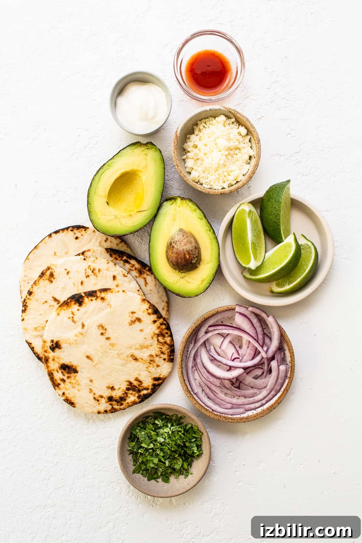 These smoked pulled pork tacos are made with our incredible, fall-off-the-bone smoked pork shoulder and all the best toppings. ingredients on countertop.