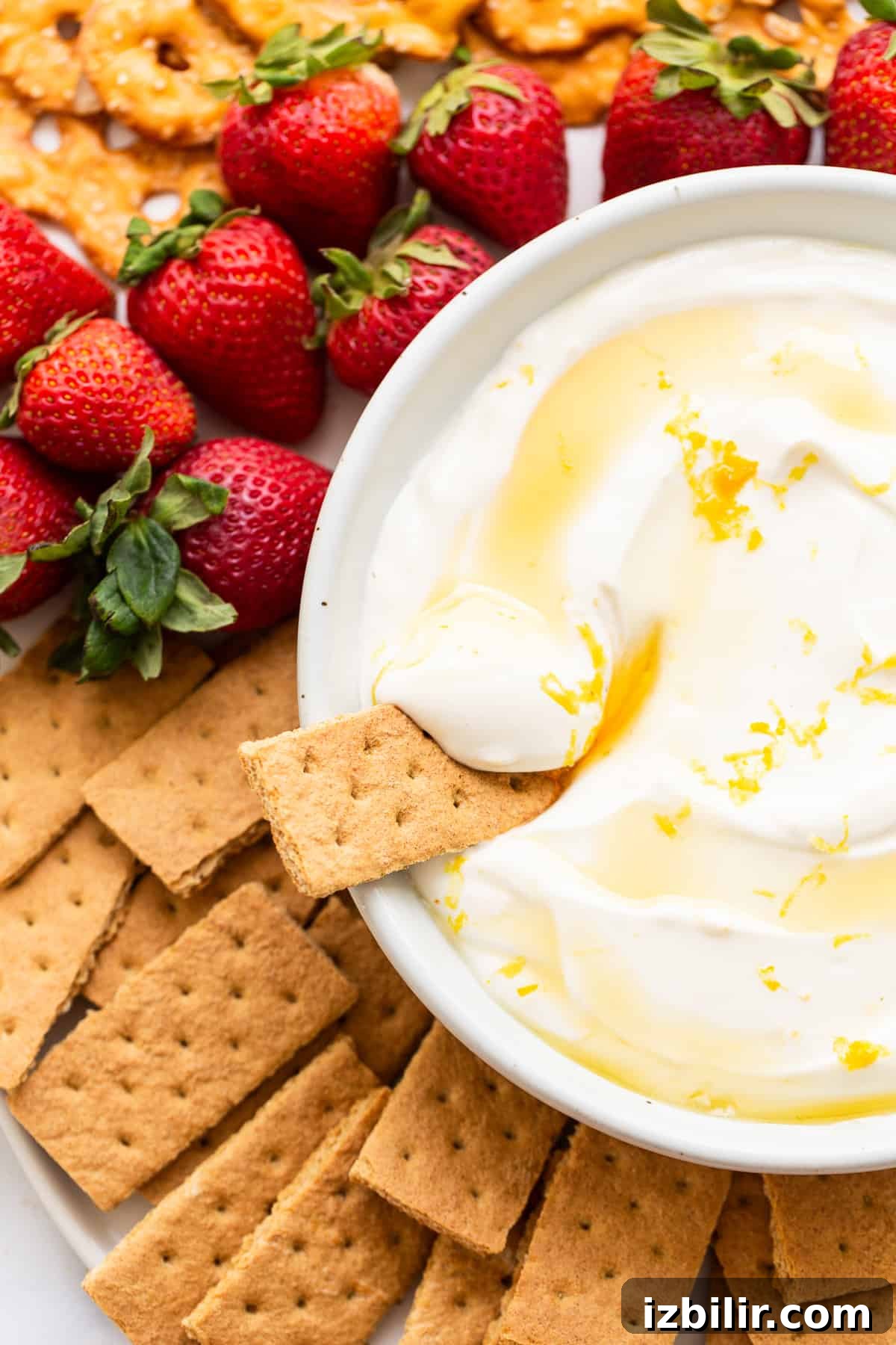 Fruit dip surrounded by strawberries and graham crackers.
