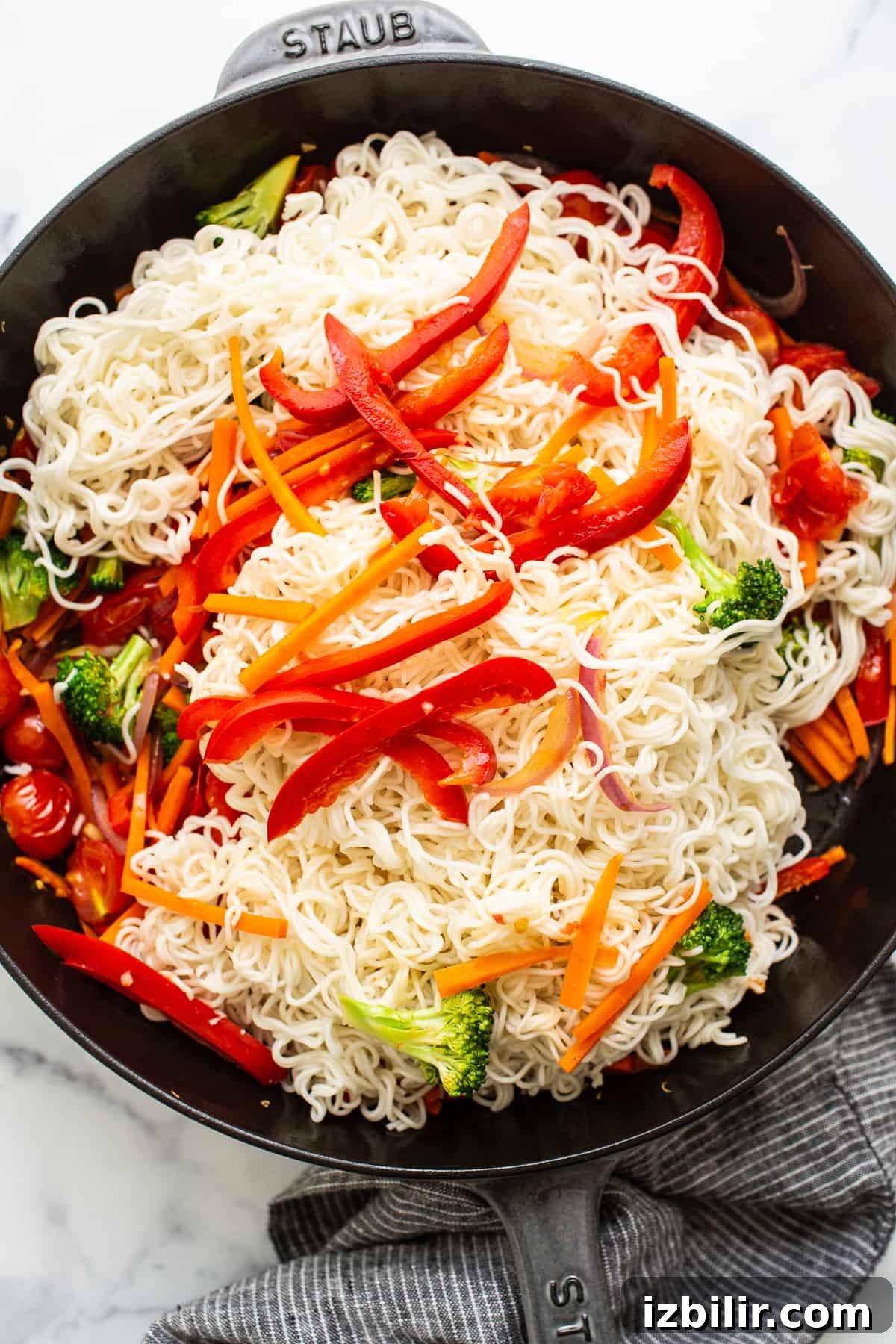 Mixing noodles with veggies.