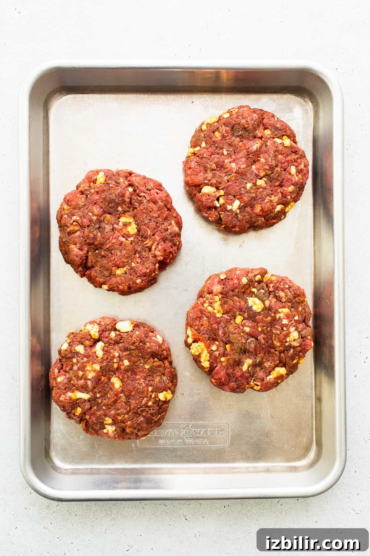 Homemade burger patties on a baking sheet.