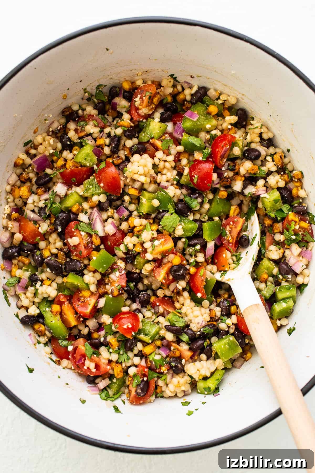 couscous salad with spoon in bowl.