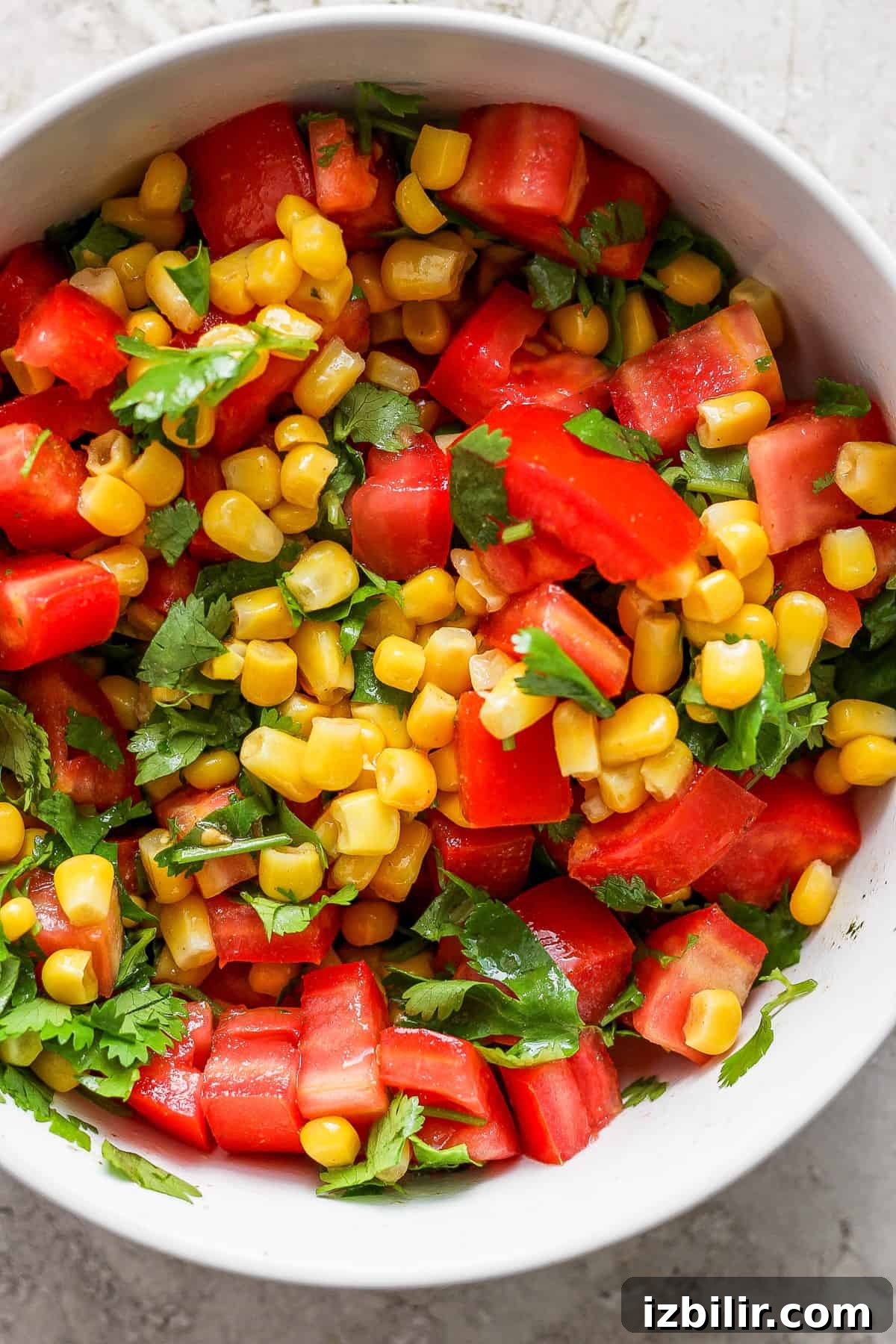 Corn and tomato salad in a white bowl.