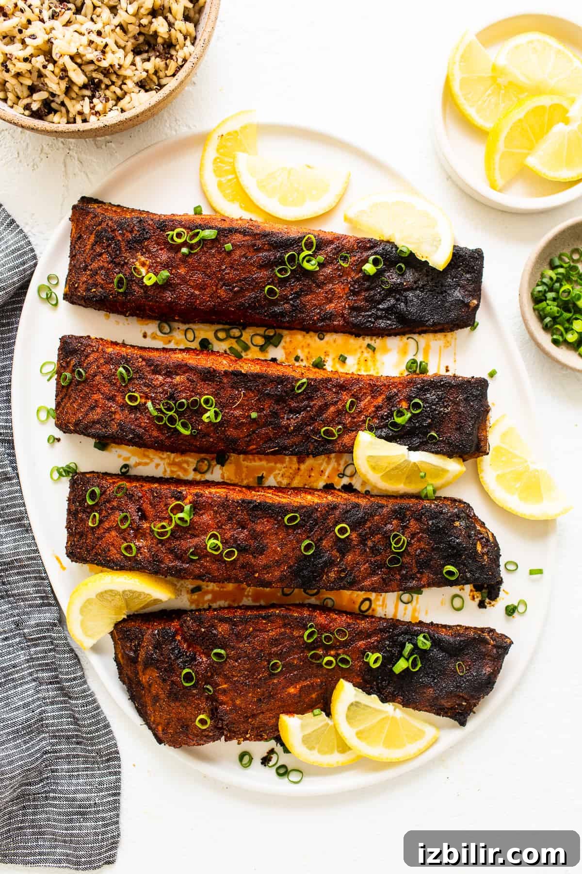 Blackened salmon on a plate with lemon slices.