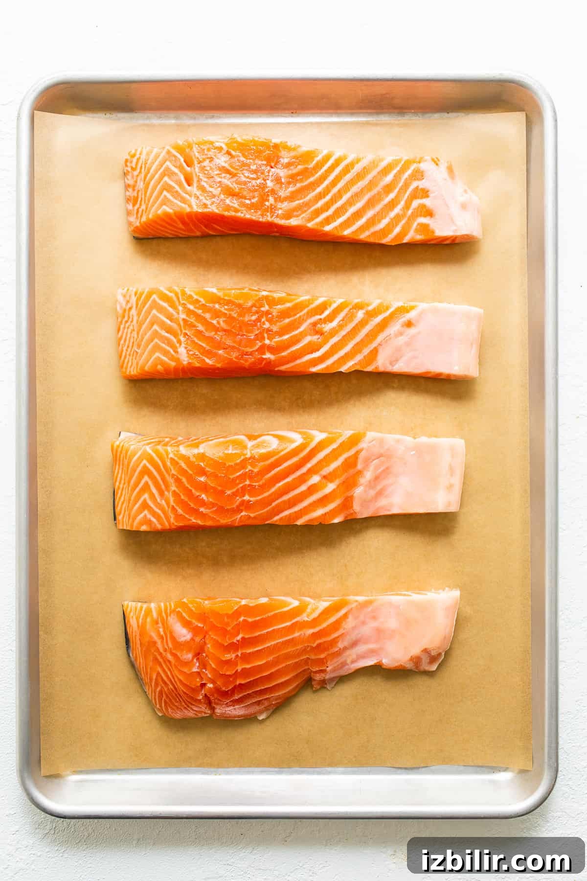Raw salmon filets on a baking sheet.