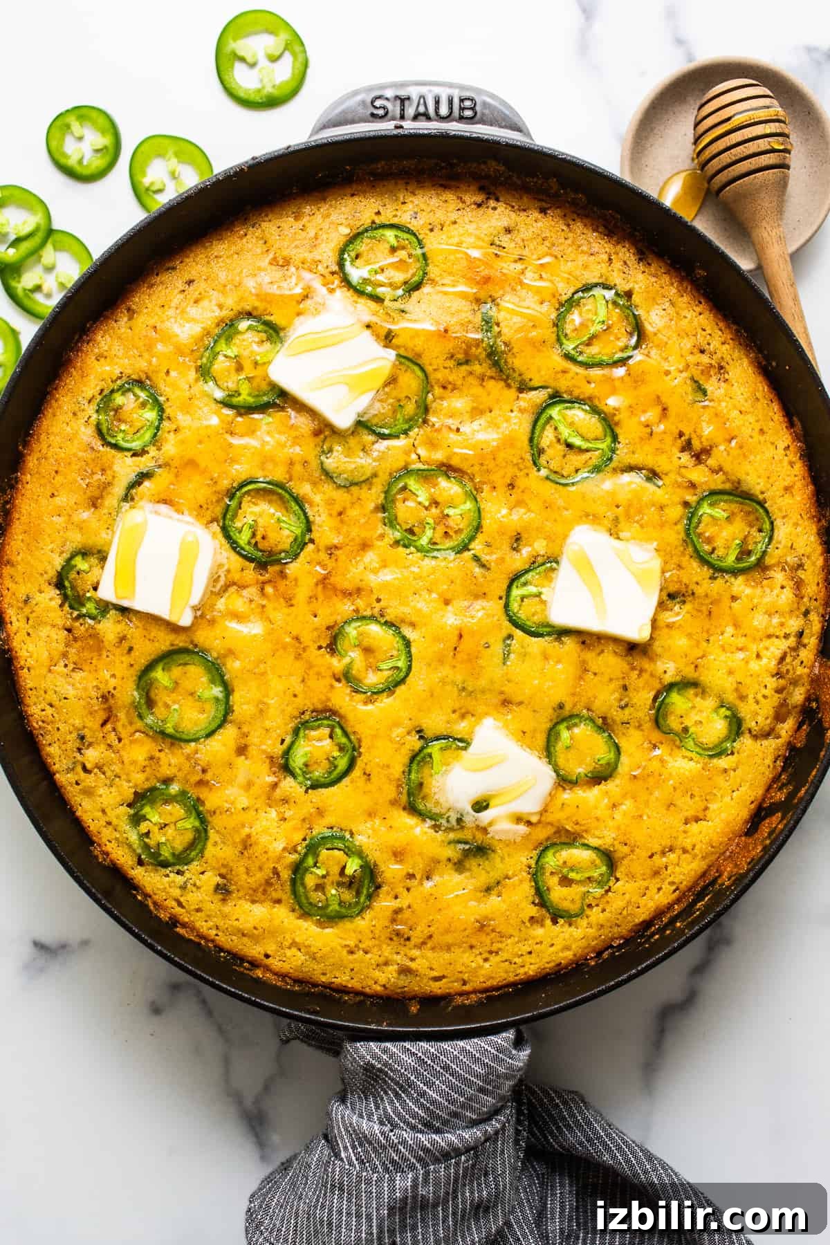 This jalapeño corn pudding recipe is made completely in a cast iron skillet in under an hour. It packs the perfect combo of sweet and spicy that you'll absolutely love! Jalapeno corn pudding in a cast iron skillet topped with pads of butter.
