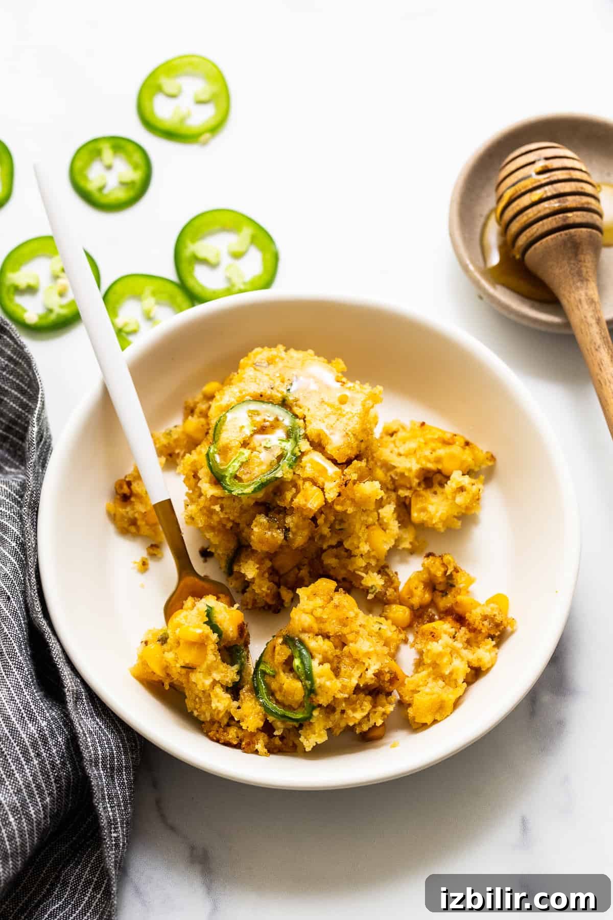 Jalapeño corn pudding served in a bowl. Jalapeno corn pudding in a bowl with a fork.