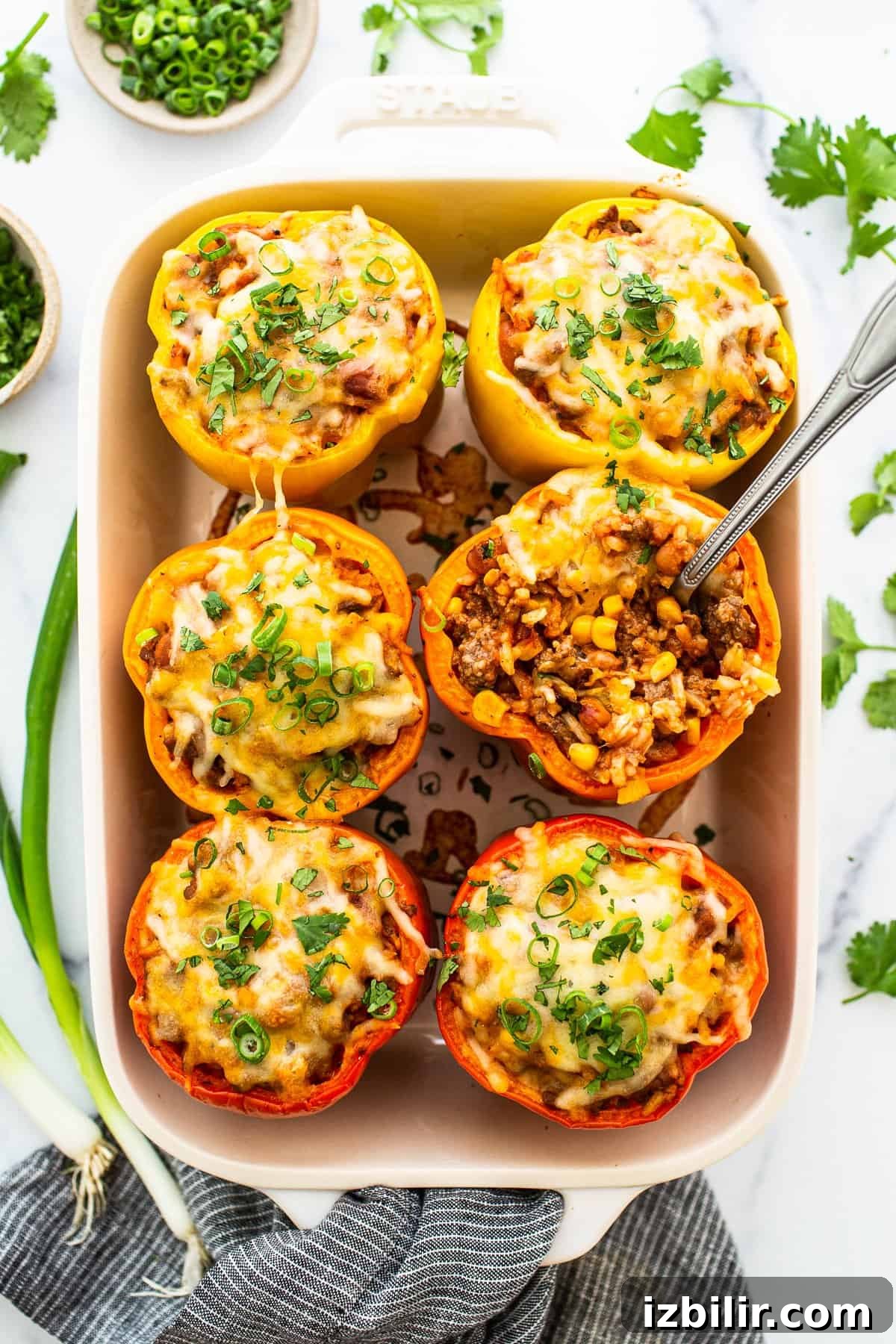 Easy stuffed peppers in a casserole dish topped with shredded cheese.