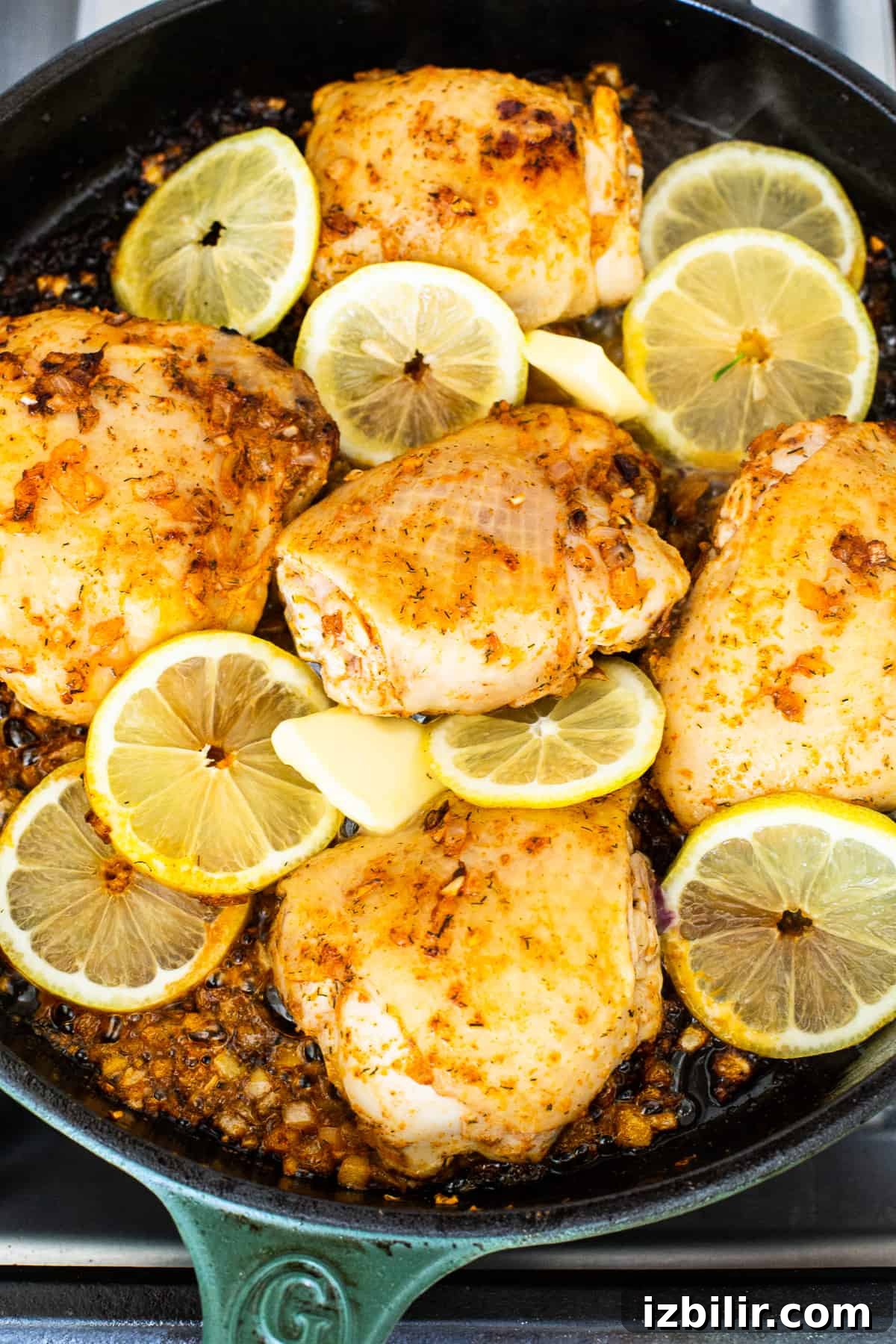 Skillet with seared chicken and lemon Chicken thighs in a skillet with lemon slices.