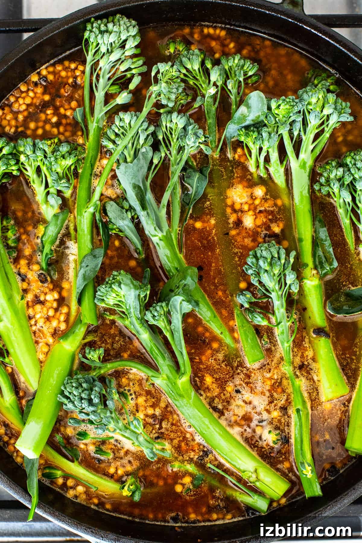 Broccolini cooking in a skillet Broccolini in a cast iron skillet.