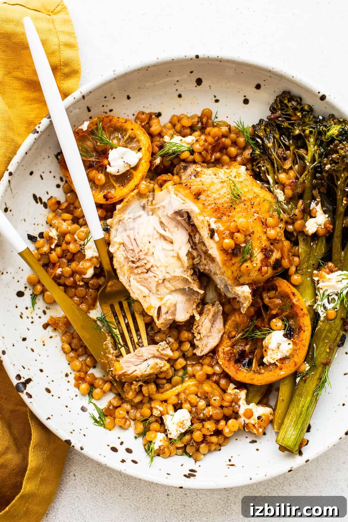 Plated lemon chicken skillet Lemon chicken skillet on a plate with broccolini and couscous.