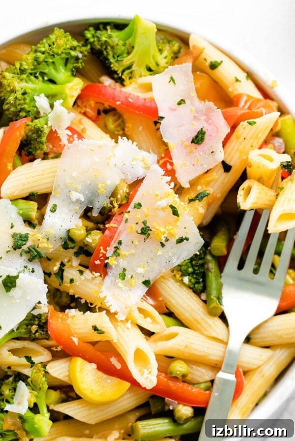 A bowl of pasta primavera with vegetables and Parmesan cheese.