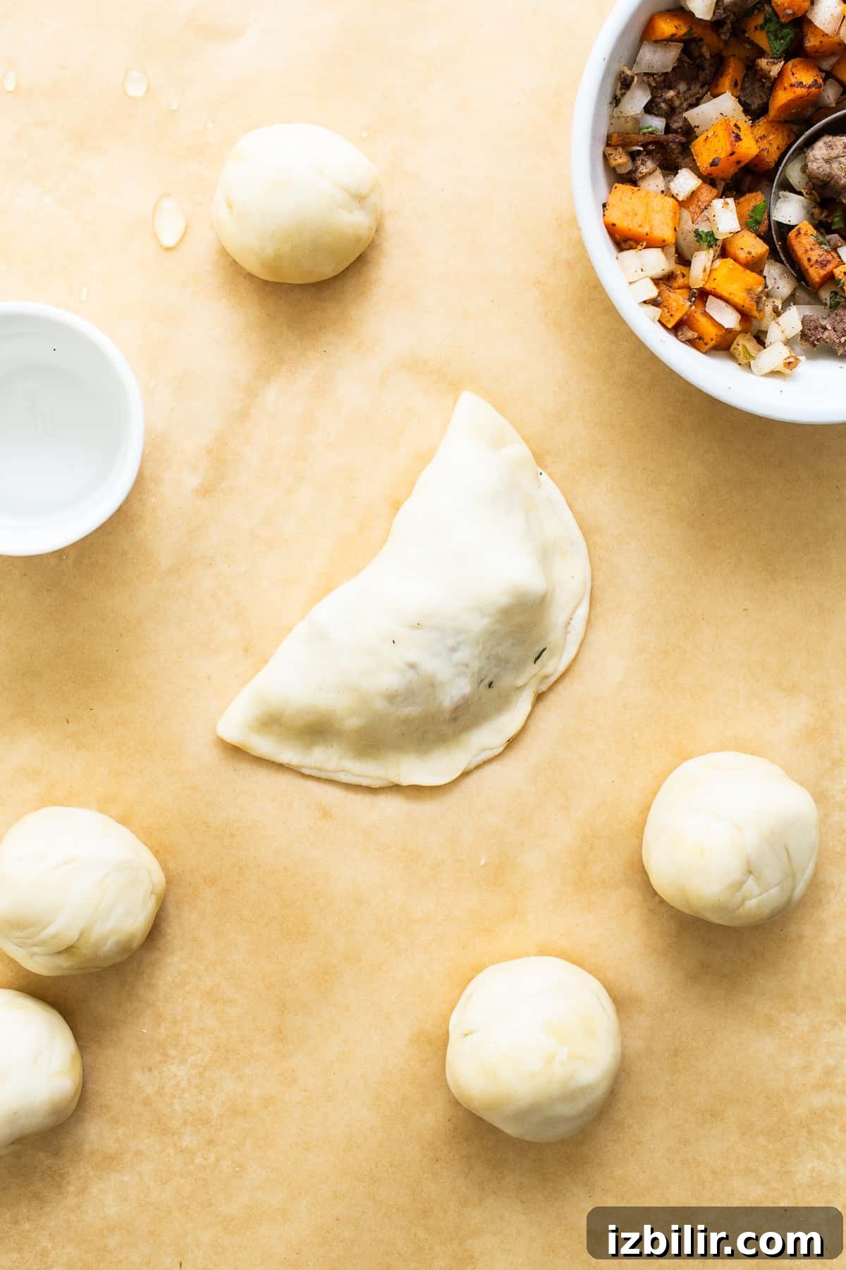 Sweet Potato Ground Beef Empanadas on parchment paper before baking.