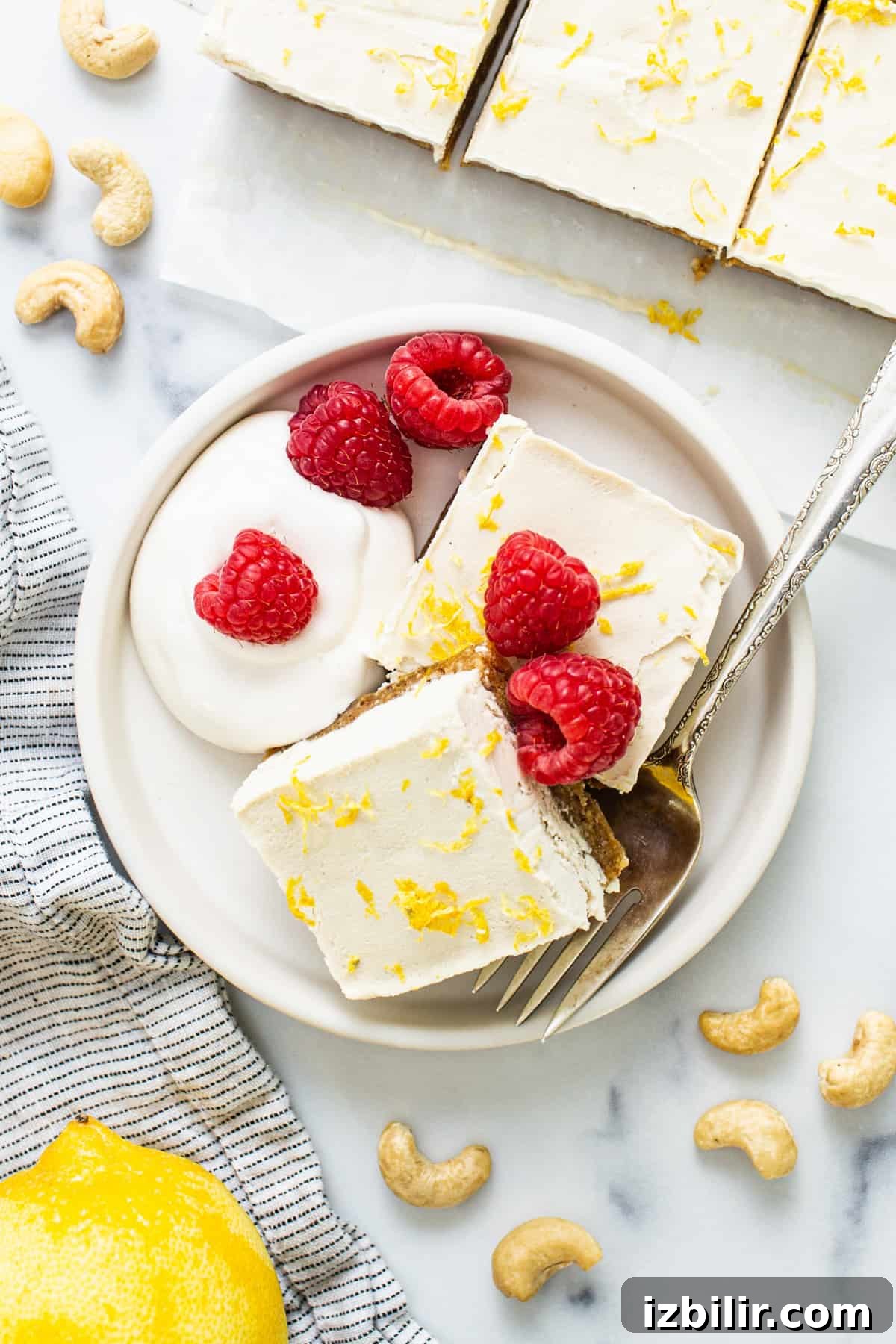 lemon bars with raspberries and cashews on a plate.