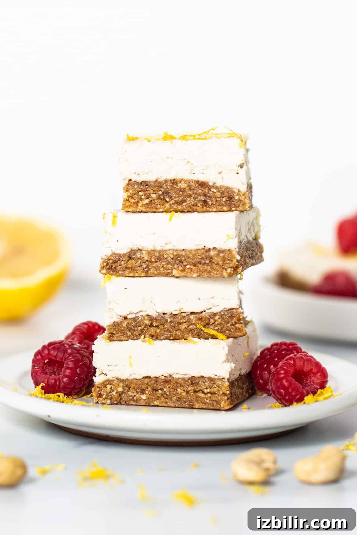 a stack of lemon bars topped with raspberries and nuts.