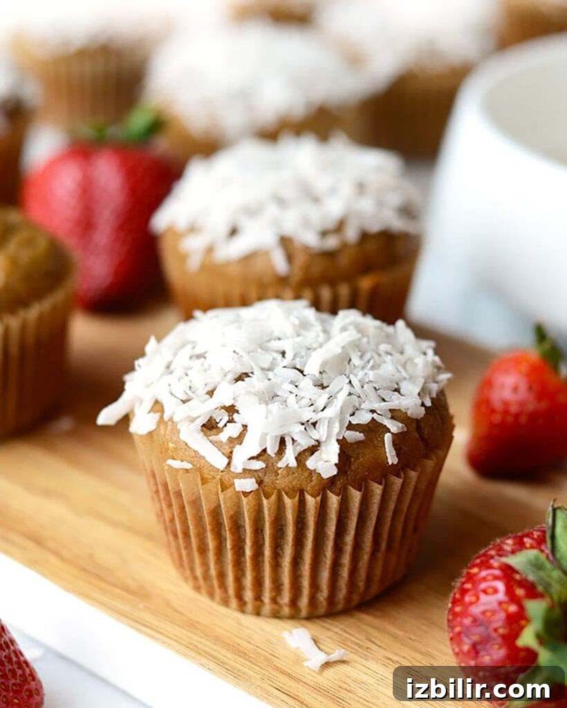 Strawberry Banana Blender Muffins: One-Bowl Recipe 4 Coconut cupcakes with strawberries on a wooden cutting board